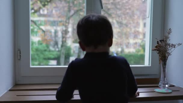 Liten Pojke Klättrar Lägenhetsfönstret För Att Blicka Över Utsikten Hemifrån — Stockvideo