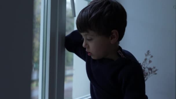无聊的孩子呆在家里无事可做 小男孩靠在玻璃窗上感到厌烦 — 图库视频影像