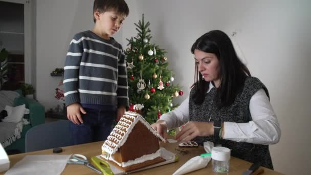 母亲和孩子创造姜饼屋 12月家庭节日与圣诞树为背景 家庭准备度假 — 图库视频影像