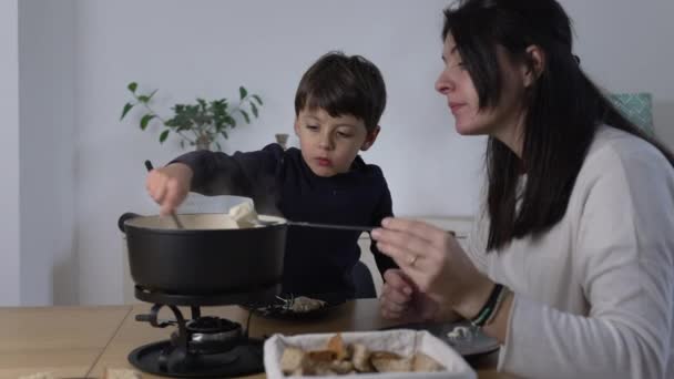 母と子シェアリングスイスフォンデュー 一緒にチーズとパンを楽しむ 伝統的なヨーロッパ料理を食べる — ストック動画