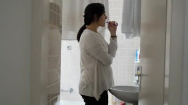 Banyoda dişlerini fırçalayan kadın, günlük aktivitelerle meşgul olan kişinin gizli sahnesi, sabah ayinlerinde diş hijyeniyle ilgilenen kadın.