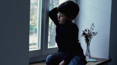 Depresyondaki çocuk pencereden dışarı bakıyor zihinsel hastalıkla boğuşuyor, düşüncelere dalmış.