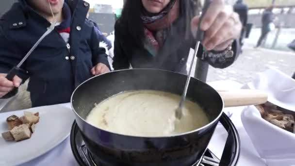 スイス フォンデュエを満喫する母と子供 寒い冬の季節にレストランでホットな伝統的なヨーロッパ料理のクローズアップ — ストック動画