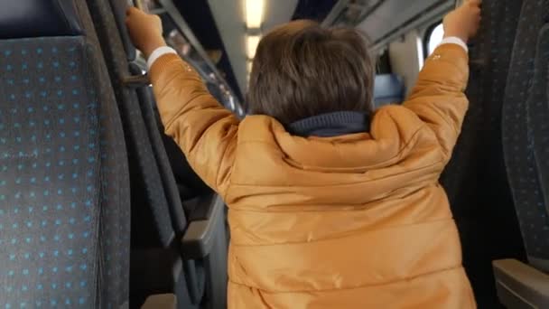 Спина Ребенка Играющего Внутри Поезда Держащегося Пассажирских Креслах Стоящих Коридоре — стоковое видео