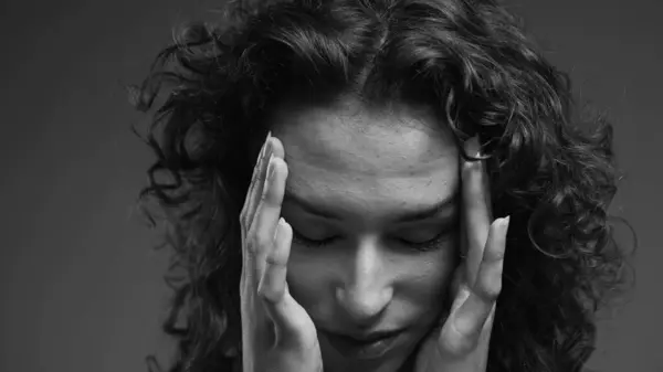 Woman feeling shame covers face with hand with deep regret, person struggling with despair and troubled introspection in intense dramatic black and white