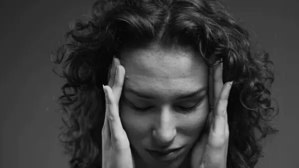 Woman feeling shame covers face with hand with deep regret, person struggling with despair and troubled introspection in intense dramatic black and white
