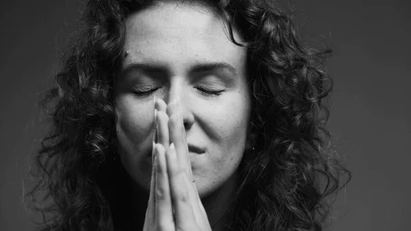 stock image Spiritual 20s person feeling GRATITUDE and Godly devotion with eyes closed and hands clenched in PRAYER. Hopeful woman having FAITH in monochromatic, black and white