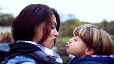 Anne ve çocuk otantik ebeveyn ve çocuk ilişkisinde öpüşürler. Anne kucağında küçük oğlunu taşıyor.