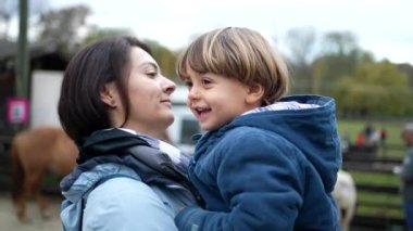 Anne ve çocuk dışarıda gerçek hayatta öpüşüyor dudaklarından öpüyor ve yan yana dans ediyor. Anne, oğlunu sonbahar mevsiminde kucağında tutuyor.