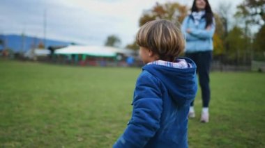 Küçük bir çocuk parkın doğasında yürüyor ve sonbahar mevsimi boyunca çevreyi gözlemlemek için duruyor.