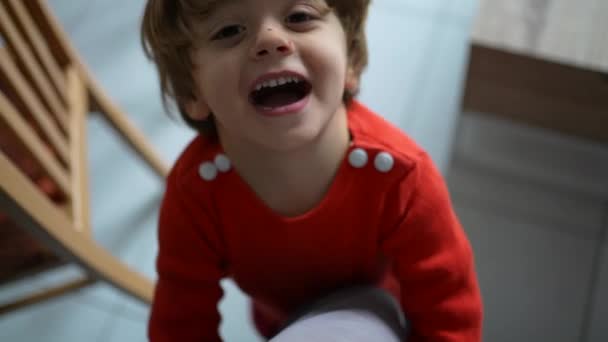 カメラの笑顔を見上げて両親の足を抱えている幸せな子供 お父さんとつながりながら喜びと喜びを感じるケアフリーの少年 — ストック動画
