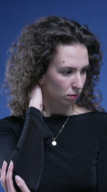 Stresli genç kadın boyun ağrısıyla boğuşuyor. Vücudunu ovuyor, endişe duyuyor.