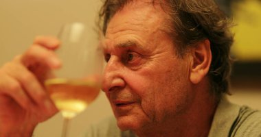 Gizli kıdemli bir adam, elinde şarap kadehiyle yemek boyunca sohbet ediyor.