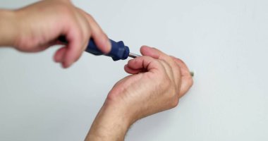 Elleri tornavidayla duvara çivi çakıyor.