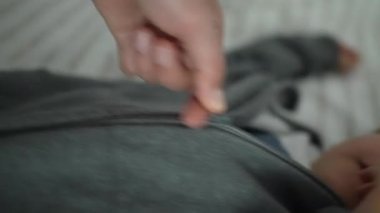 Sonbahar sonbahar sezonunda annesinin ceketinin fermuarını çekmesi. Çocuk kalın giysilerle dışarı çıkmaya hazırlanıyor.