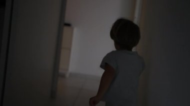 Evin koridorunda koşan küçük çocuğun arkası, evin içinde koşan çocuğun gölgesi.