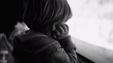 Trenle seyahat ederken üzgün, düşünceli bir çocuk. Depresyondaki yolcu cam pencereye yaslanmış melankolik ve endişeli hissederken siyah ve beyaz yolda gidip geliyor.