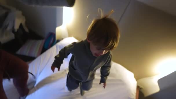 休暇中の家族の喜び 親と息子がホテルベッドでバウンス — ストック動画