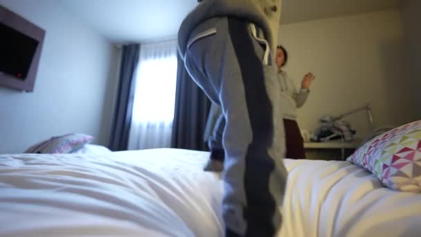 ベッドで跳ねる子供 家族の休暇 ホテルのベッドシートで飛び降りる小さな男の子 — ストック動画
