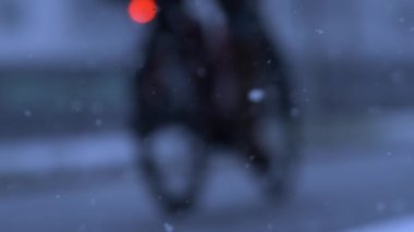 Person riding bicycle amidst snowfall in city captured in super slow motion at 1000 fps, urban environment during winter season