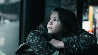 Melancholic little girl staring at view from bus seat, close-up face of contemplative child daydreaming, sad depressed expression