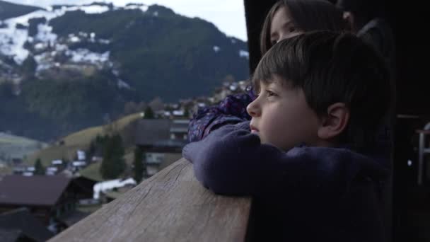 Kind Lehnt Hölzernem Chalet Balkon Und Starrt Winter Auf Die — Stockvideo