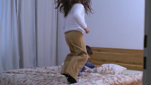 快乐的兄弟姐妹在睡衣的卧室里跳跃 快乐的家庭生活方式时刻 — 图库视频影像