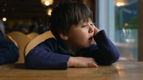 Menino Pequeno Entediado Bocejando Enquanto Espera Mesa Restaurante Pela Janela — Vídeo de Stock
