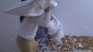 Yastık savaşına katılan çocukların eğlenceli aktiviteleri havada uçuşan tüylerle birlikte yüksek hızlı kamerayla süper yavaş çekimde görüntüleniyor.