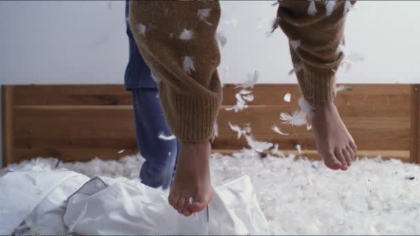 衣衫褴褛的孩子们的脚在床上跳着 羽毛在空中飞舞 动作非常慢 孩子玩耍时的无忧无虑的童年情绪 — 图库视频影像