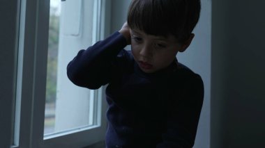 Sıkıcı çocuk evde sıkışmış, pencereye yaslanmış, evde sıkıntıyla boğuşan manzarayı seyrediyor.