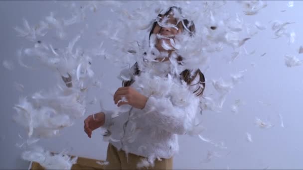 一个无忧无虑的小女孩以1000 Fps的速度向空中抛掷羽毛 孩子们童年幸福的时刻被羽毛覆盖着 — 图库视频影像