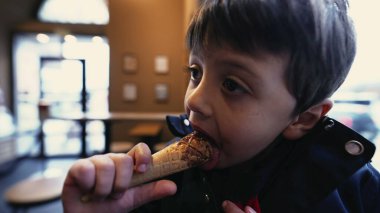 Çocuk, Cafe with City 'de dondurma külahının tadını çıkarıyor. Arka planda Motion View var.