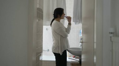 Sabah ritüeli sahnesinde kadın dişlerini fırçalarken aynaya bakıyor. Açık sözlü kadın alışkanlığı diş fırçasıyla ağız temizleme alışkanlığı.