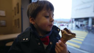 Arka planda, pencereye bakan bir çocuğun dondurma zevkini tatması. Tatlı tatlı yiyen küçük çocuk.