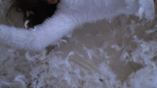 快乐的小女孩躺在床上 数以千计的羽毛在空中飘扬 用1000英尺的高速相机拍摄 在羽毛中微笑的孩子 — 图库视频影像