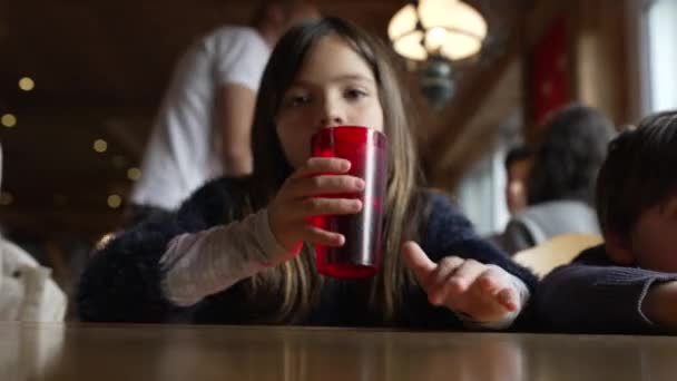 Liten Flicka Dricksvatten Från Plast Röd Kopp Restaurang Väntar Mat — Stockvideo