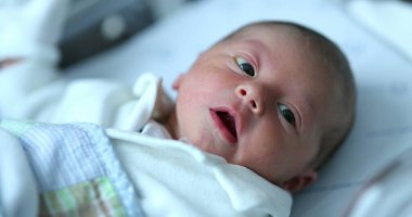 Newborn baby at hospital nursery after birth, first day of infant life inside crib