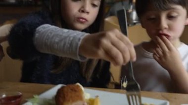 Çocuklar restoranda patates kızartması yiyor. Kardeşler lokantada yemek yiyor. Aile hafta sonu aktivitesi, erkek ve kız kardeş öğle yemeği zamanı.