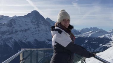 İkonik platformda dikilen kadının portresi Grindelwald 'ın ilk göz alıcı manzarası. Kış kıyafetleri giymiş ve kameraya gülümsüyor.