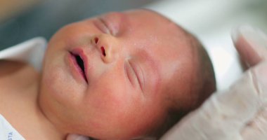 Newborn baby bath after birth relaxing with eyes closed falling asleep