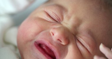 Newborn baby close-up face crying, first day of life