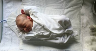 Newborn baby asleep in crib, vertical shot of infant