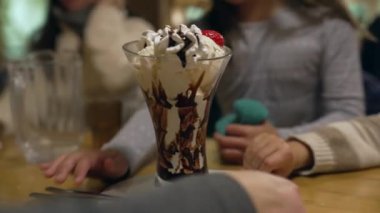 Restoran masasında dondurma servis etmek, çocuklar kaşık kapıp akşam yemeğinde tatlı yemek, kardeşler kremalı şekerli yiyeceklerin tadını çıkarıyorlar.