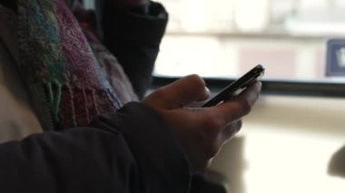 Trenin içindeki telefon cihazına bakan kişi, ulaşımda cep telefonu aygıtını kontrol eden kişi.
