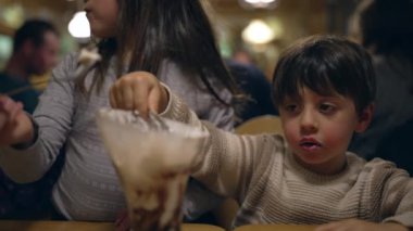 Restoranda dondurma yiyen genç bir çocuk. Şekerden hoşlanan çocuk tatlıya düşkündür.
