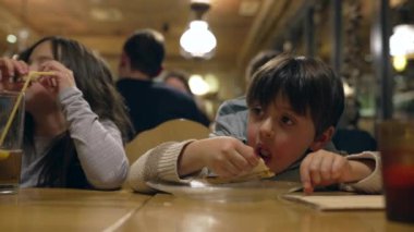 Küçük çocuk restoranda pizza yiyor, çocuk akşam yemeğinde karbonhidrat yiyor.