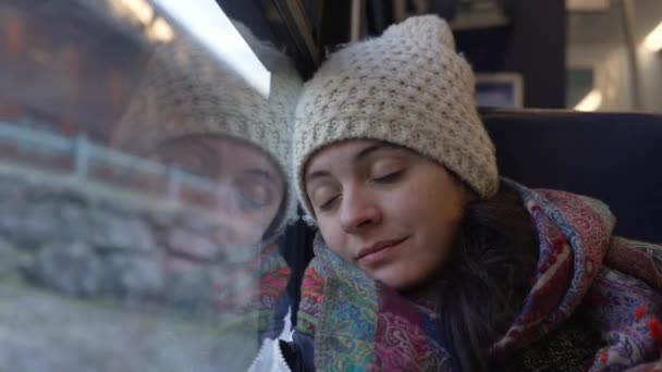 乗客の女性は列車の窓に頭を傾けながら 景色の眺めは背景で通過します 交通機関の通勤中に寝ている人 — ストック動画