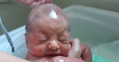 close-up of baby in small bathtub, Washing little newborn baby face and body