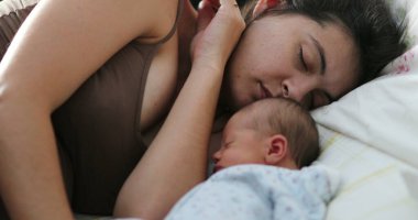 Candid mom and baby asleep in bed together
